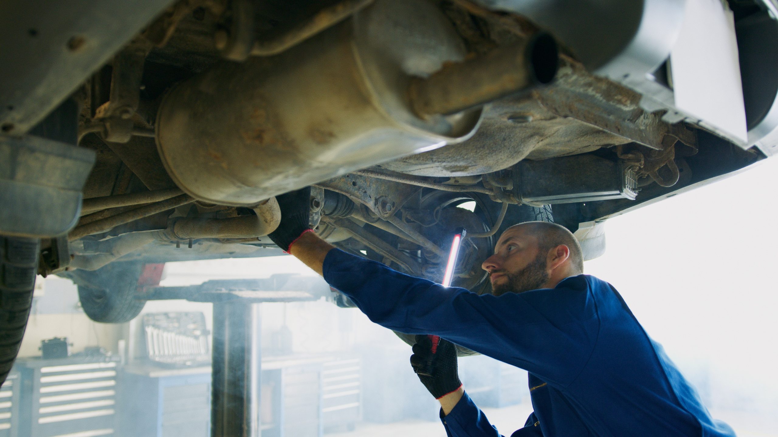 Top Three Reasons to Upgrade Your Exhaust System - Mechanic under car near exhaust