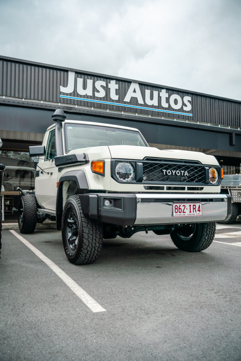 The front of Toyota's 2024 70 series in white, sitting outside Just Autos performance specialists in Nambour