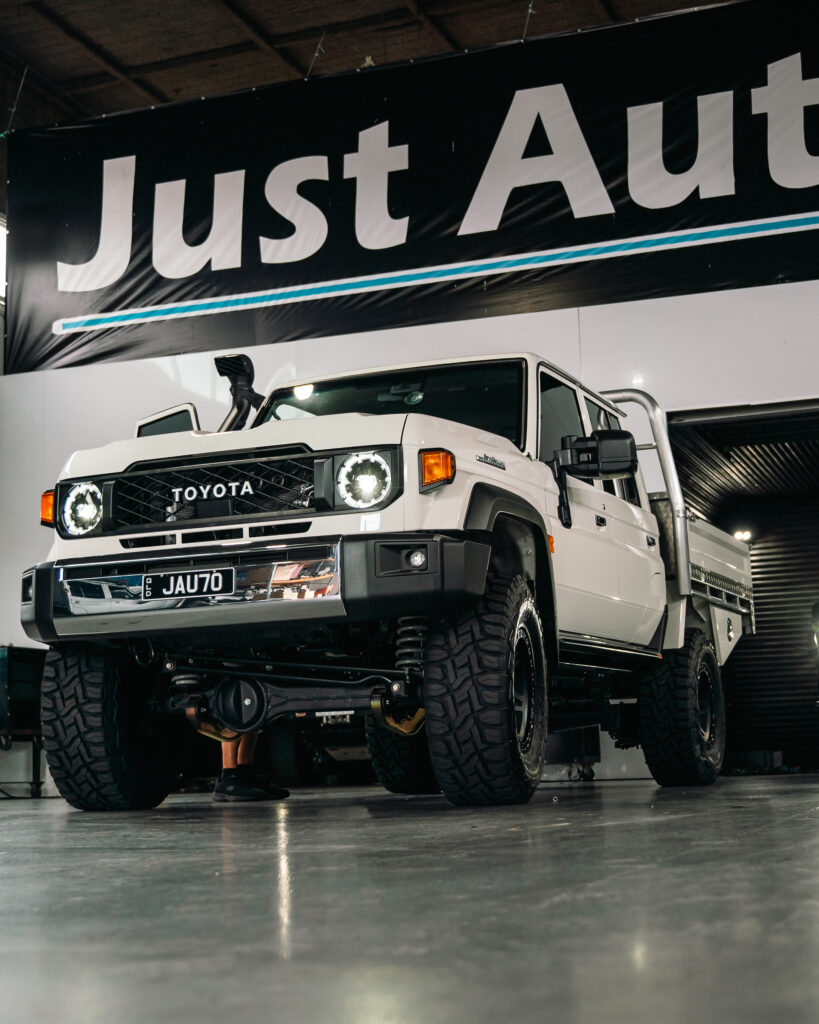 White Toyota 79 Series dual cab under Just Autos workshop banner